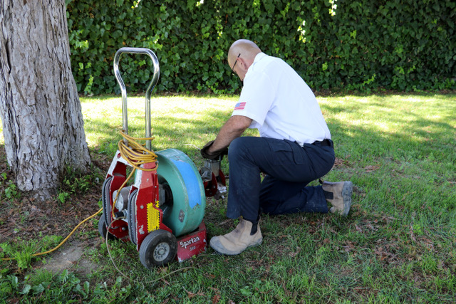 a man performing drain cleaning with auger machine