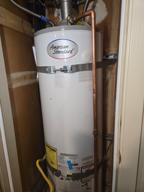 American Standard water heater in a closet with copper piping and yellow gas line